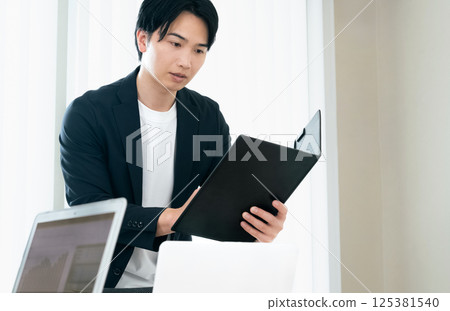 A casual-style businessman examining documents A casual-style businessman examining documents 125381540
