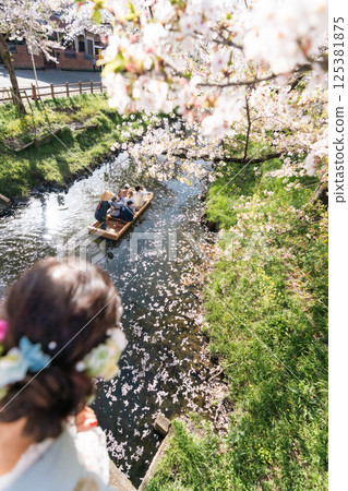 A middle-aged woman in a kimono sightseeing with a small boat crossing the Shingashi River, turned into a flower raft 125381875