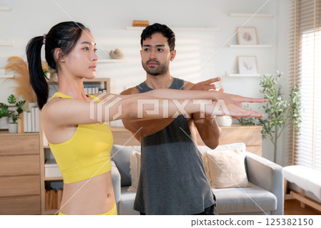 Fitness coach guidance with asian woman during squat training at home in living room. 125382150