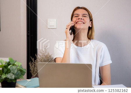 Young caucasian businesswoman talking with smartphone and working on laptop computer. 125382162