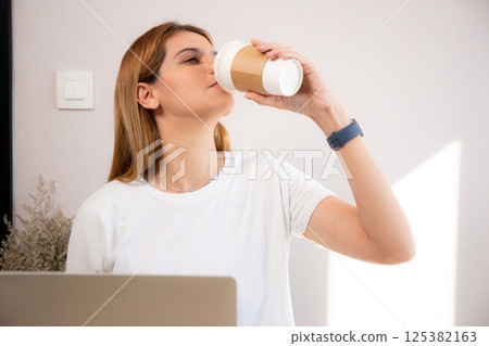 Happiness young caucasian businesswoman drinking coffee while working on laptop computer. 125382163