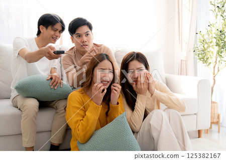 Group asian friends watching a horror movie at home with reaction with fear and surprise. Group asian friends watching a horror movie at home with reaction with fear and surprise. 125382167