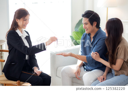 Happy asian couple receiving house key from real estate agent after success property purchase home. Happy asian couple receiving house key from real estate agent after success property purchase home. 125382220