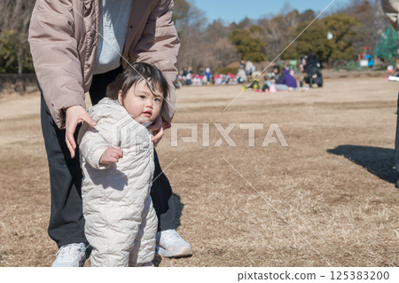 [A one-year-old child and his mother playing on the grass at Sagamihara City Asamizo Park] 125383200
