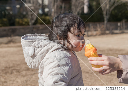 【相模原市麻溝公園，一名一歲小孩和媽媽在草地上玩耍，補充水分】 125383214