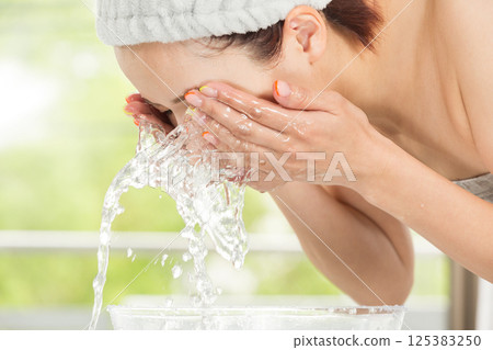 Young Asian woman is washing her face. 125383250