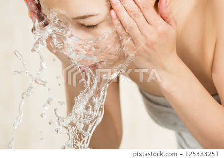 年輕的亞洲女子正在洗臉。 年輕的亞洲女子正在洗臉。 125383251