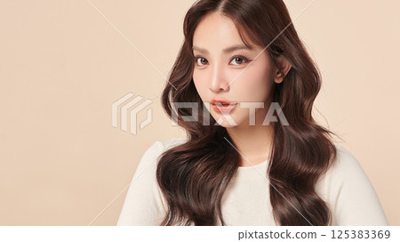 A beautiful young Asian woman with clean, fresh skin against a beige background. Skincare, facial treatment, cosmetology, beauty, and spa. An elegant portrait of an Asian woman. 125383369