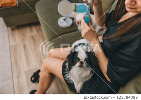 close-up of hands and serum, cozy home setting concept of daily beauty routines, pet companionship, wellness 125384089