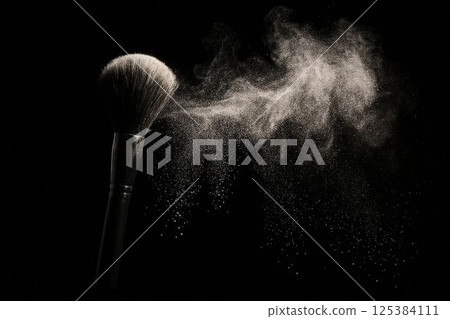Makeup brush releasing powder cloud in dramatic studio lighting 125384111