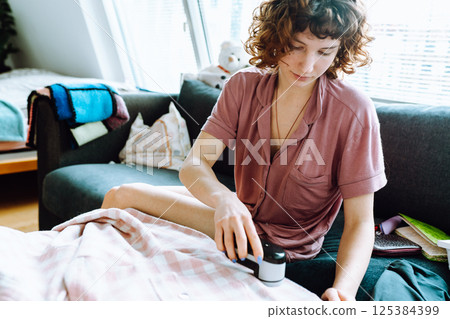 woman takes care of clothes at home, cuts off lint with tool 125384399