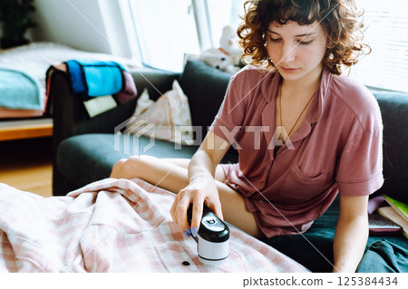 woman takes care of clothes at home, cuts off lint with tool woman takes care of clothes at home, cuts off lint with tool 125384434