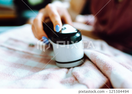 woman takes care of clothes at home, cuts off lint with tool woman takes care of clothes at home, cuts off lint with tool 125384494