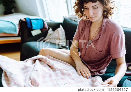 woman takes care of clothes at home, cuts off lint with tool woman takes care of clothes at home, cuts off lint with tool 125384527