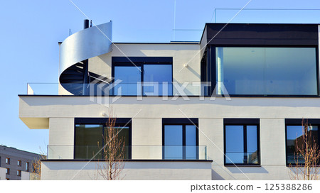 Modern architecture of urban residential apartment buildings on a sunny day. Low-rise apartment buildings with large windows and extensive terraces. White facade of a modern apartment building. Modern architecture of urban residential apartment buildings on a sunny day. Low-rise apartment buildings with large windows and extensive terraces. White facade of a modern apartment building. 125388286