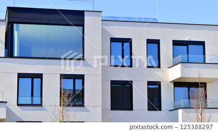 Modern architecture of urban residential apartment buildings on a sunny day. Low-rise apartment buildings with large windows and extensive terraces. White facade of a modern apartment building. 125388297