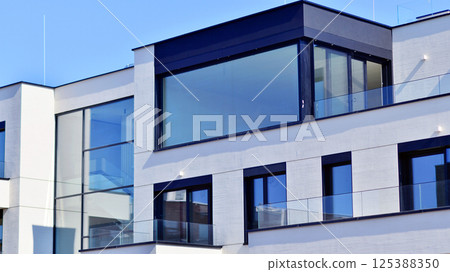 Modern architecture of urban residential apartment buildings on a sunny day. Low-rise apartment buildings with large windows and extensive terraces. White facade of a modern apartment building. 125388350