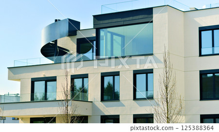 Modern architecture of urban residential apartment buildings on a sunny day. Low-rise apartment buildings with large windows and extensive terraces. White facade of a modern apartment building. Modern architecture of urban residential apartment buildings on a sunny day. Low-rise apartment buildings with large windows and extensive terraces. White facade of a modern apartment building. 125388364