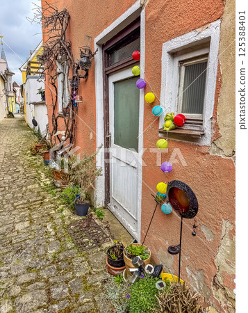 Charming alley with decorated door, colorful lights, and potted plants outside. High quality photo 125388401