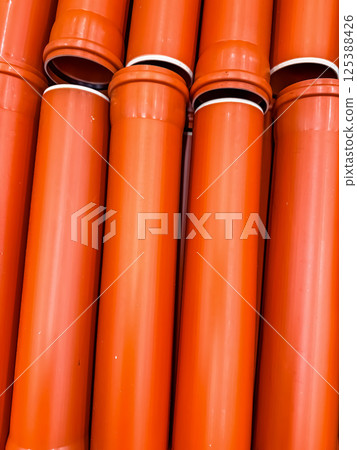 Stack of orange plastic drainage or plumbing pipes displayed in hardware store. High quality photo Stack of orange plastic drainage or plumbing pipes displayed in hardware store. High quality photo 125388426