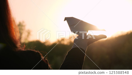 woman holding paper bird sunset symbolizes freedom and hope. silhouette against sky expresses desire for independence. paper 125388548