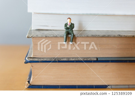 桌上一本打開的英文書和一個穿西裝的男性形象學習、學習、再學習的形象 桌上一本打開的英文書和一個穿西裝的男性形象學習、學習、再學習的形象 125389109
