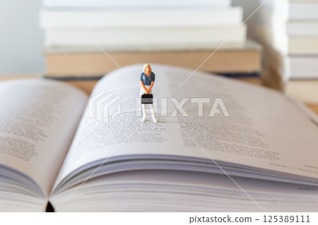 一本打開的英文書和桌上的一個女性身影，學習、學習、再學習的形象 125389111