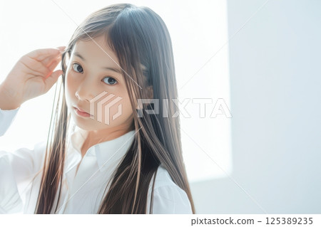 Japanese girl touching her long hair (elementary school student, model, kid model, hair problems, curly hair, treatment) 125389235