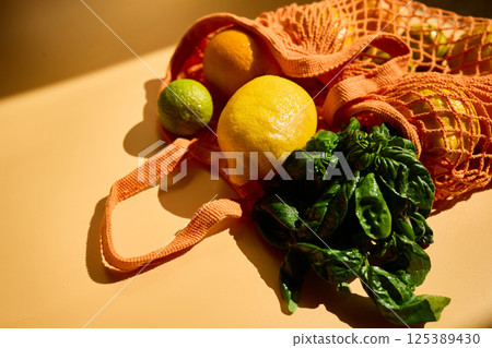 Fresh fruits and herbs in a colorful netted bag highlighting eco grocery shopping practices Fresh fruits and herbs in a colorful netted bag highlighting eco grocery shopping practices 125389430