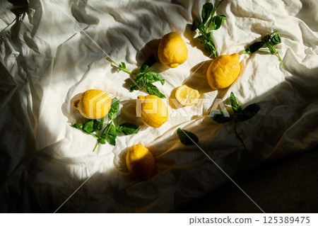 Bright yellow lemons and fresh basil leaves create a vibrant summer arrangement in Italy Bright yellow lemons and fresh basil leaves create a vibrant summer arrangement in Italy 125389475