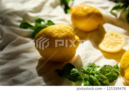 Bright yellow lemons and fresh basil leaves create a vibrant summer arrangement in Italy Bright yellow lemons and fresh basil leaves create a vibrant summer arrangement in Italy 125389476
