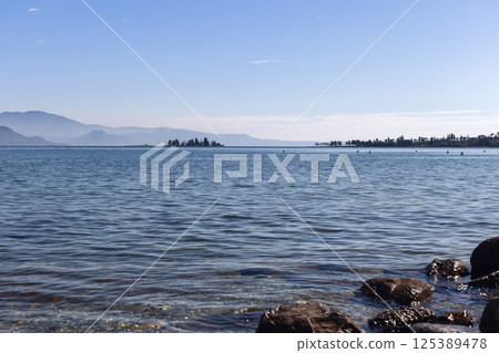 Crystal-clear water along shore of Lake Garda in Italy with San Biagio island 125389478