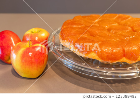 Close-up view of homemade Tarte Tatin with golden caramelized apple topping on a glass plate 125389482