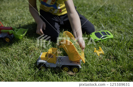 A child plays with toy cars on the lawn in the sunny day 125389631