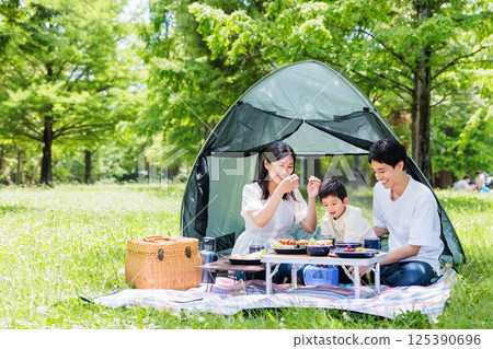 友善的家庭在營地享受烹飪，戶外形象 125390696