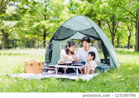 友善的家庭在營地享受烹飪，戶外形象 125390700