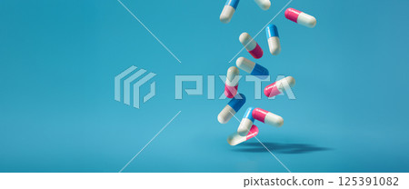 Antibiotics A blue and pink pill is falling On a Isolated Blue Background Antibiotics A blue and pink pill is falling On a Isolated Blue Background 125391082