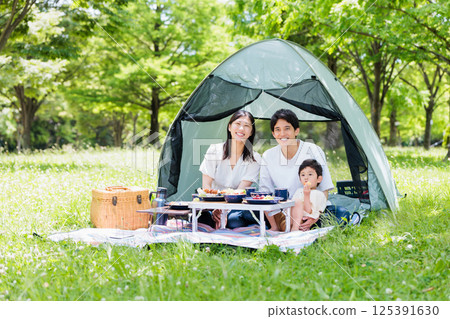 友善的家庭在營地享受烹飪，戶外形象 125391630