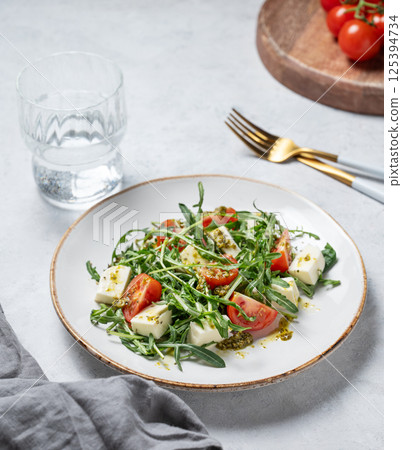 Healthy arugula salad with cherry tomatoes, mozzarella and pesto sauce on a plate Healthy arugula salad with cherry tomatoes, mozzarella and pesto sauce on a plate 125394734