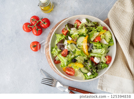 Fresh vegetable salad with feta cheese and olives on plate on a light background. 125394838