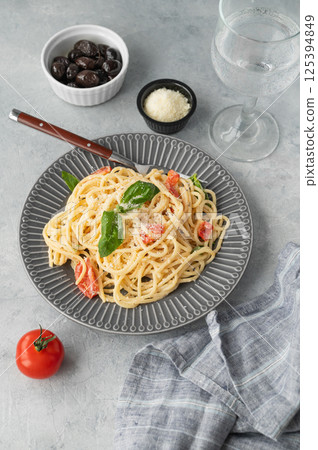 Creamy spaghetti with cherry tomatoes, parmesan cheese and basil on a plate on a light background 125394849