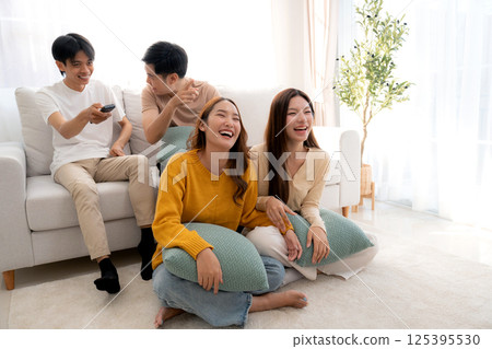 Group young asian friends watching TV together in a cozy living room at home with happy. 125395530