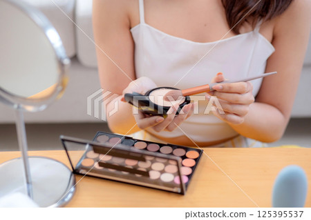 Closeup hands beauty happy young woman applying makeup with brush looking mirror. 125395537