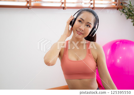 Young asian woman listening music on headphone after practice yoga and workout with relax. 125395550