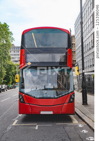 Front view of a red London double decker bus, showcasing the sharp design and clean lines. The surrounding urban landscape and buildings reflect in the bus windows. Front view of a red London double decker bus, showcasing the sharp design and clean lines. The surrounding urban landscape and buildings reflect in the bus windows. 125396046