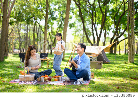 Cheerful family enjoys a picnic near tent at a forest campsite Cheerful family enjoys a picnic near tent at a forest campsite 125396099