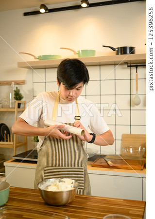 Asian male baker wrapping whipped cream for storage 125396258