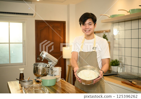 Proud home baker holds a bowl of freshly whipped cream in a kitchen 125396262