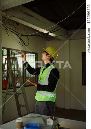 Construction supervisor evaluating ceiling installation in an unfinished room Construction supervisor evaluating ceiling installation in an unfinished room 125396293