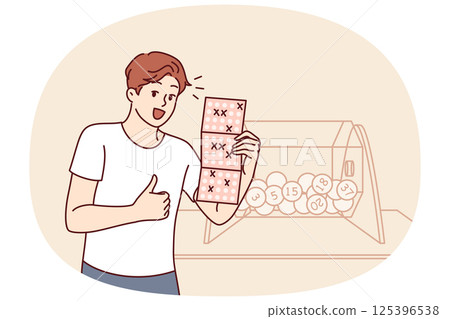 Man won bingo lottery happily demonstrates winning ticket and stands near transparent box with balls 125396538